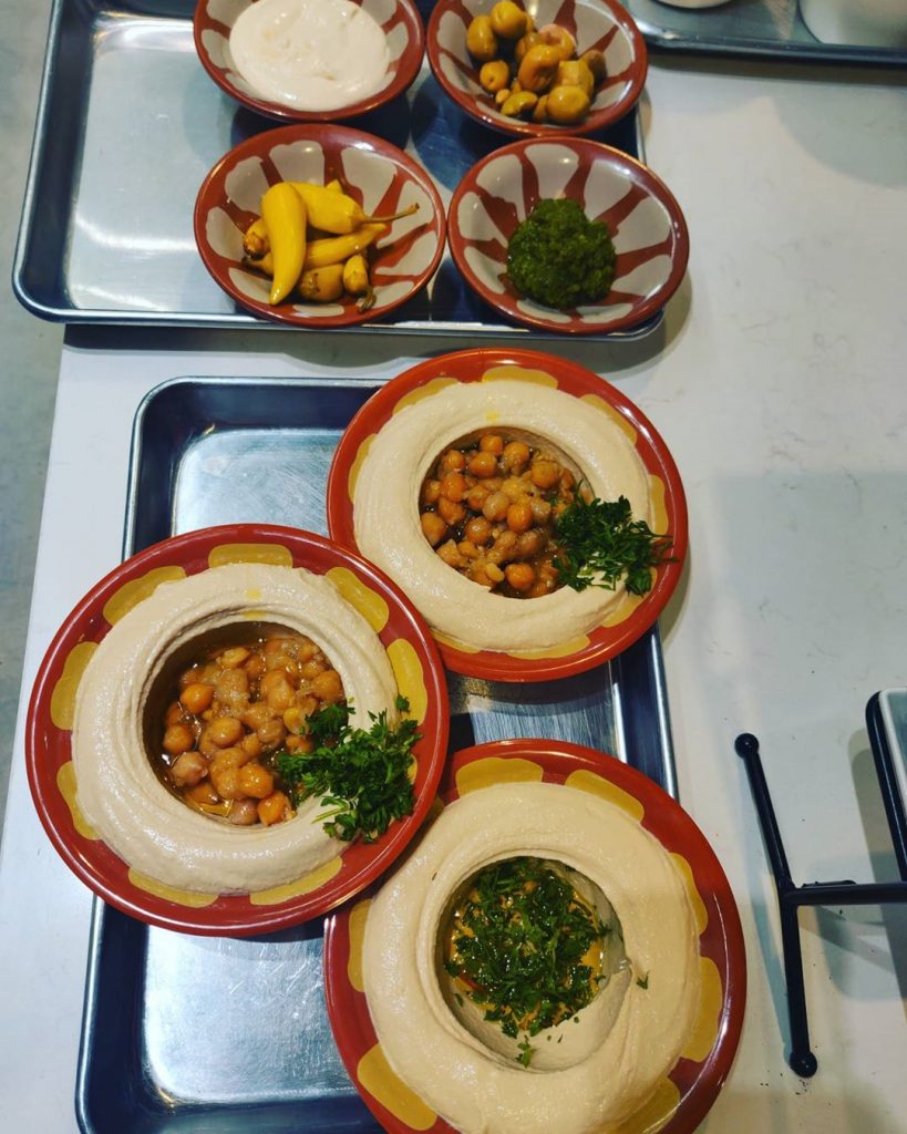 3 plates of hummus and 4 bowls of sides