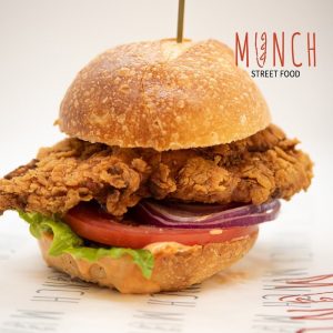fried chicken on a burger bun with lettuce, tomato and onion