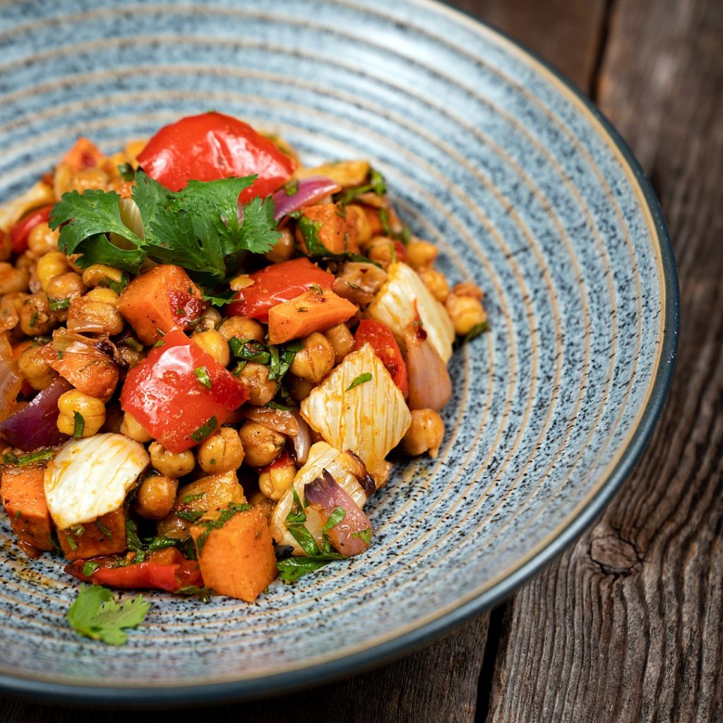 a spiced chickpea and roasted vegetable salad with fresh herbs, served in blue bowl