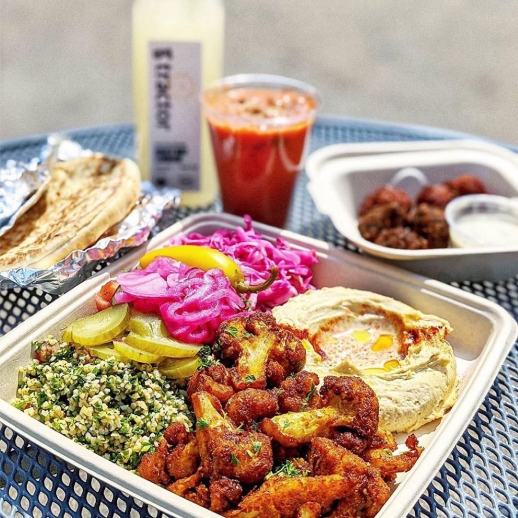 a table with a mixed plate of food, a drink and pita