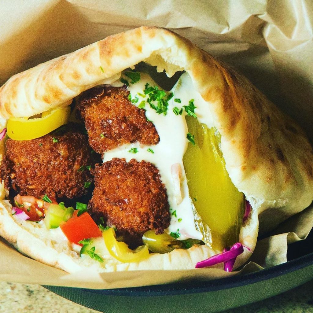 a pita stuffed with falafel, tahini, pickles and other vegetables