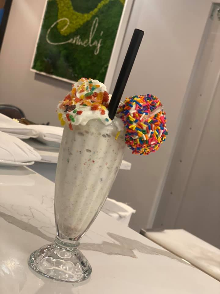 a vanilla and sprinkle milkshake with a black straw resting on a table