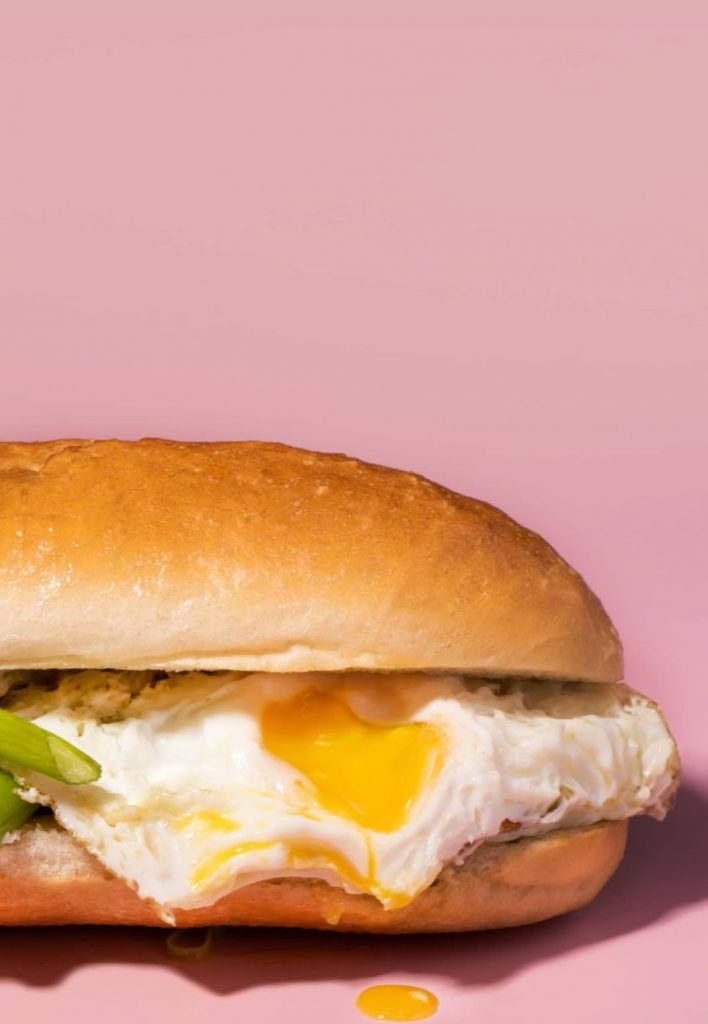an egg sandwich on a pink background