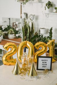 gold 2021 balloons with a happy new year letter board and gold party hats