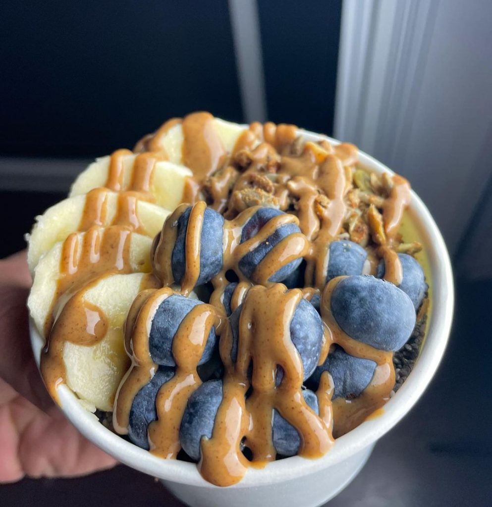 an oatmeal bowl with nuts, banana, blueberries and almond butter