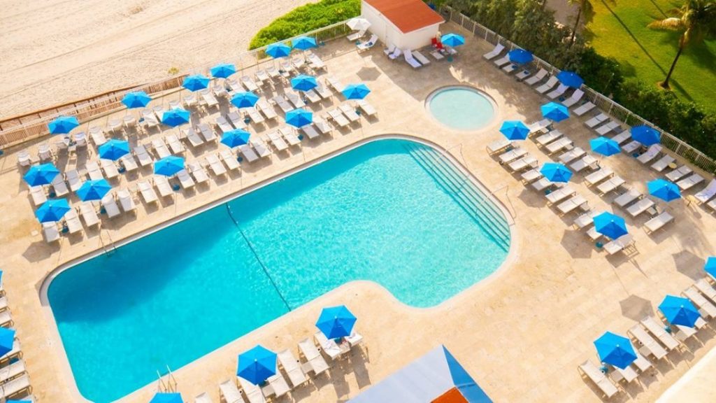 an aerial view of a pool, lounge chairs and umbrellas