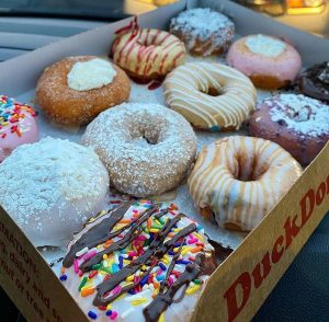 a dozen assorted donuts in a duck donuts box