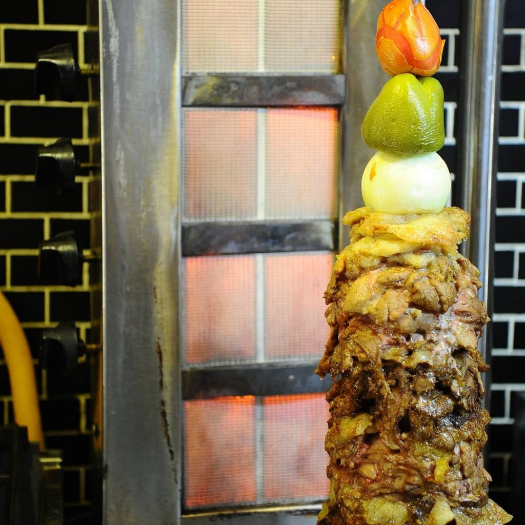 a shawarma on a spit with peppers an onions