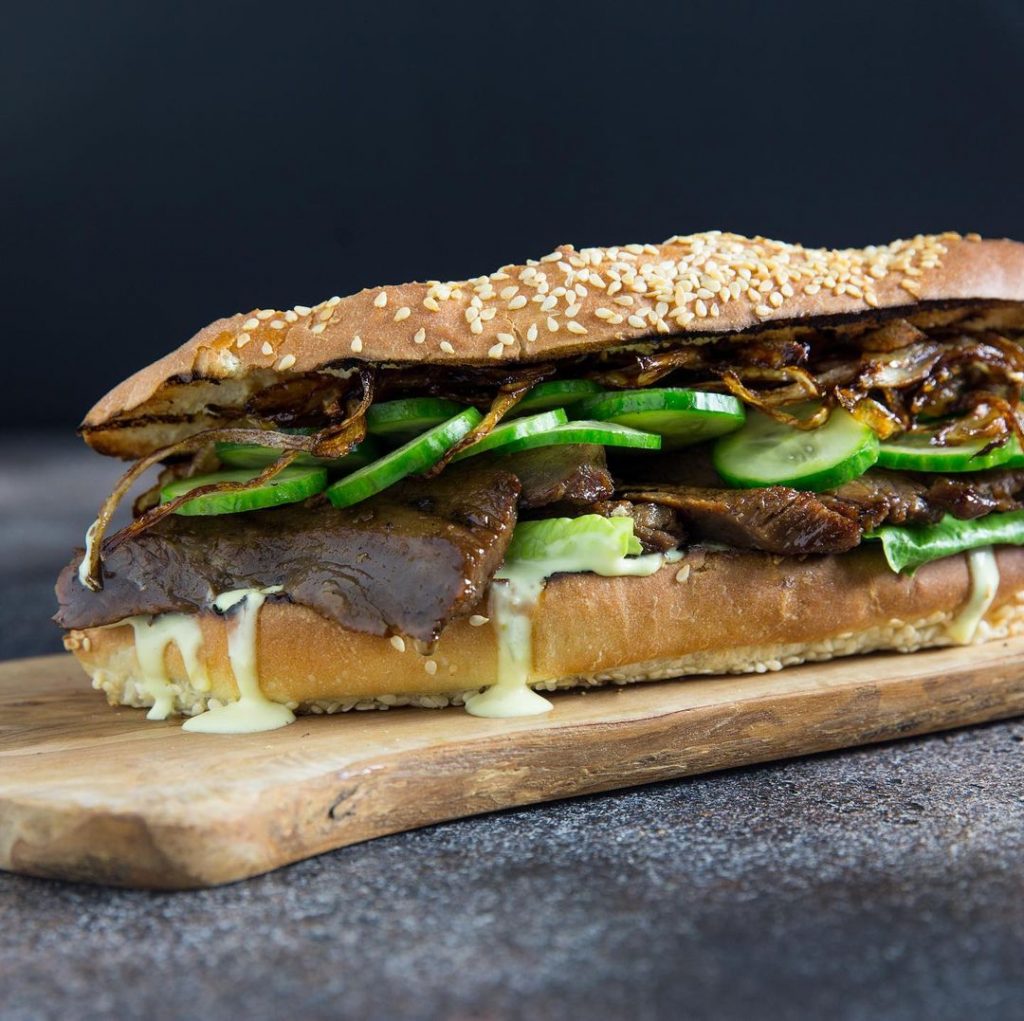 a steak sandwich on a sesame seed baguette