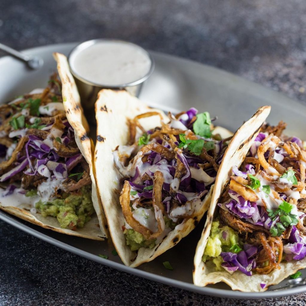 three pulled beef tacos and a white dressing