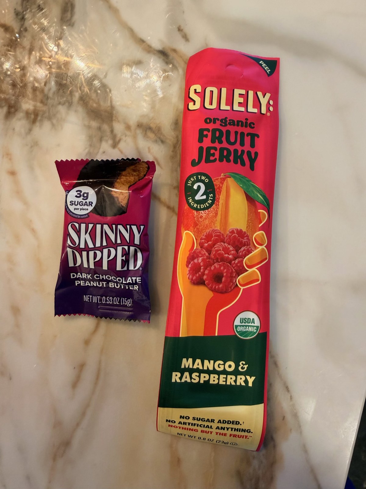 Skinny Dipped dark chocolate peanut butter cup and Solely organic mango raspberry fruit jerky